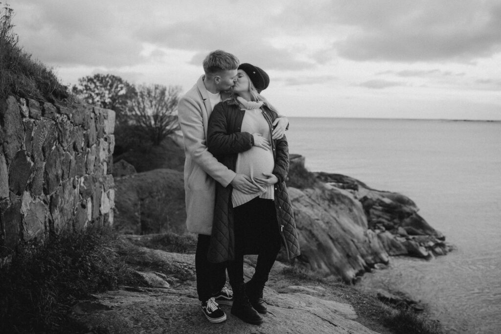 odotuskuvaus suomenlinnassa, meri näkyy taustalla ja pariskunta suutelee toisiaan