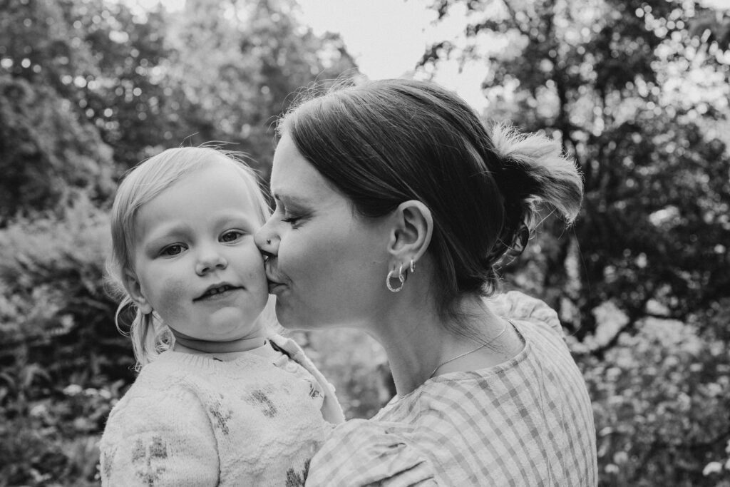 mustavalkoisessa kuvassa taapero ja äiti, lähikuva miljöössä