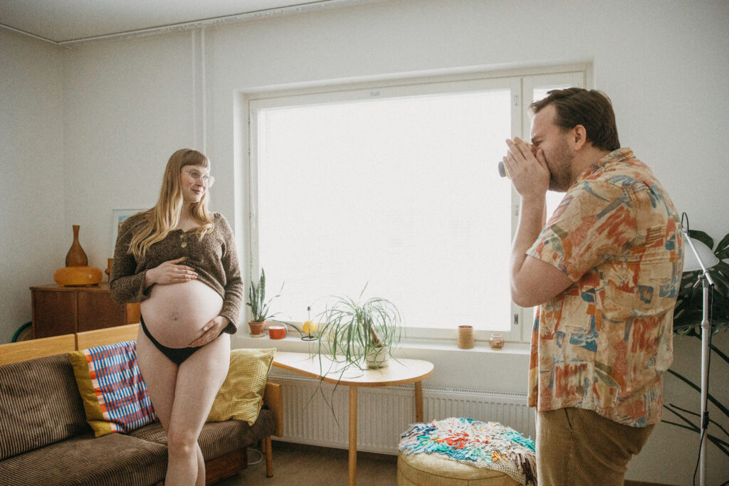 Raskauskuvaus kotona Helsingissä mies valokuvaa odottavaa puolisoa