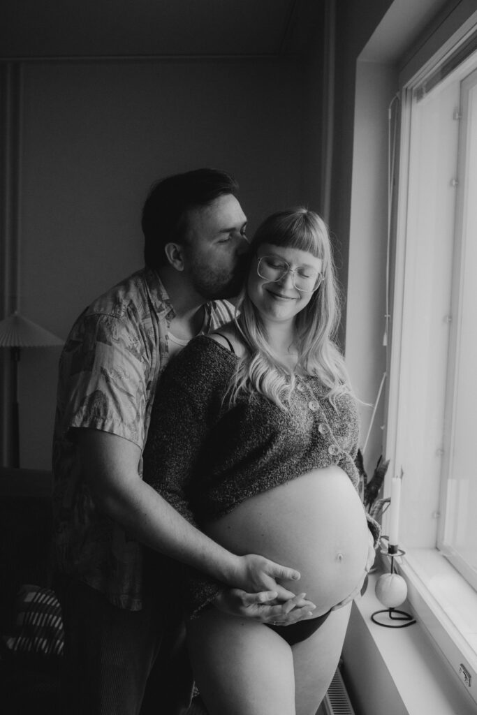 mustavalkoinenkuva olohuoneessa missä puolisokuvaa odottavaa äitiä