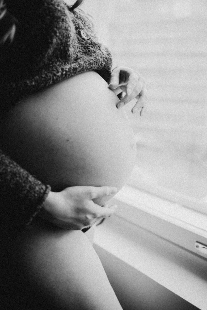 kauniskuva missä odottava nainen pitää käsiä mahalla