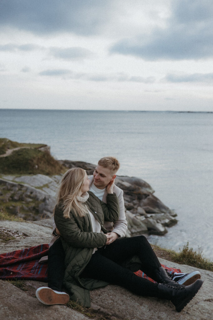 meritatakana ja pariskunta istuu suomenlinnan kalliolla ja he odottavat ensimmäistä vauvaansa