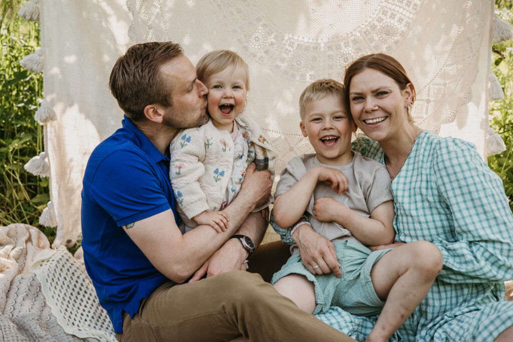 lapset nauravat omenapuun alla perhekuvauksessa