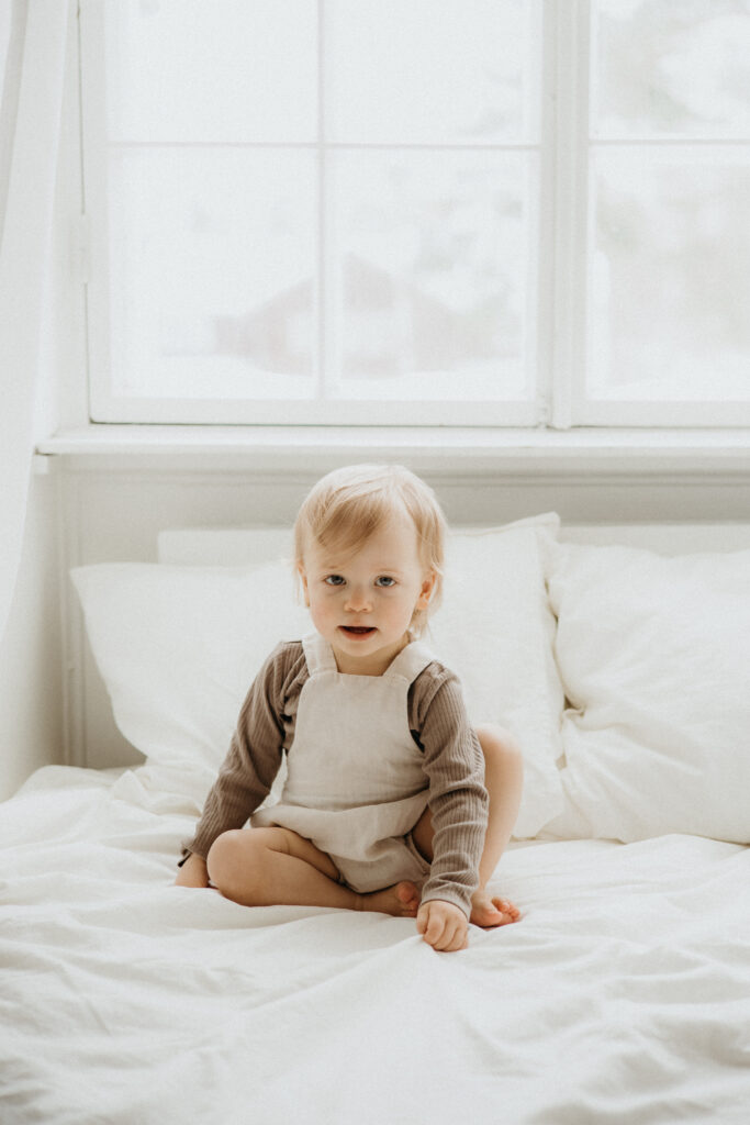 studiokuva lapsesta joka istuu sängyssä