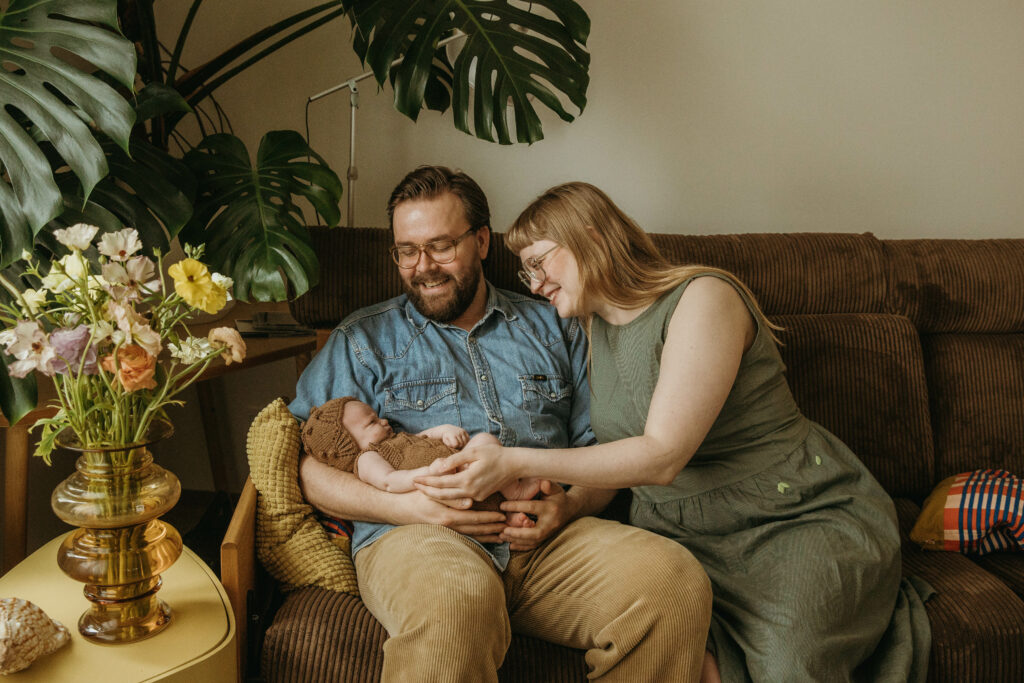 vastasyntyneen vauvan sormia ihaillaan niin että vauva on isän sylissä.