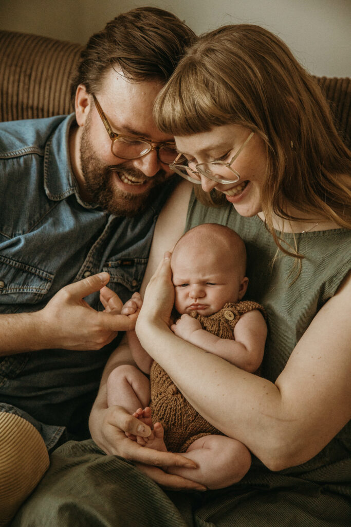lähikuva vanhemmista jotka pitävät vastasyntynyttä vauvaa sylissä