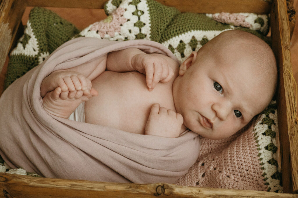 vauva kuvattuna yksin vastasyntyneen kuvauksessa kotona. Vauva on kääritty kapaloon